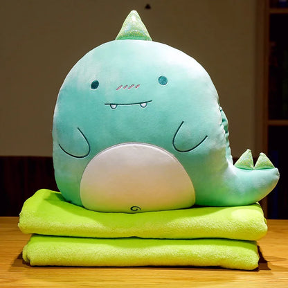 Dinosaur animal cushion blanket with mint-green plush face on folded green blanket layers