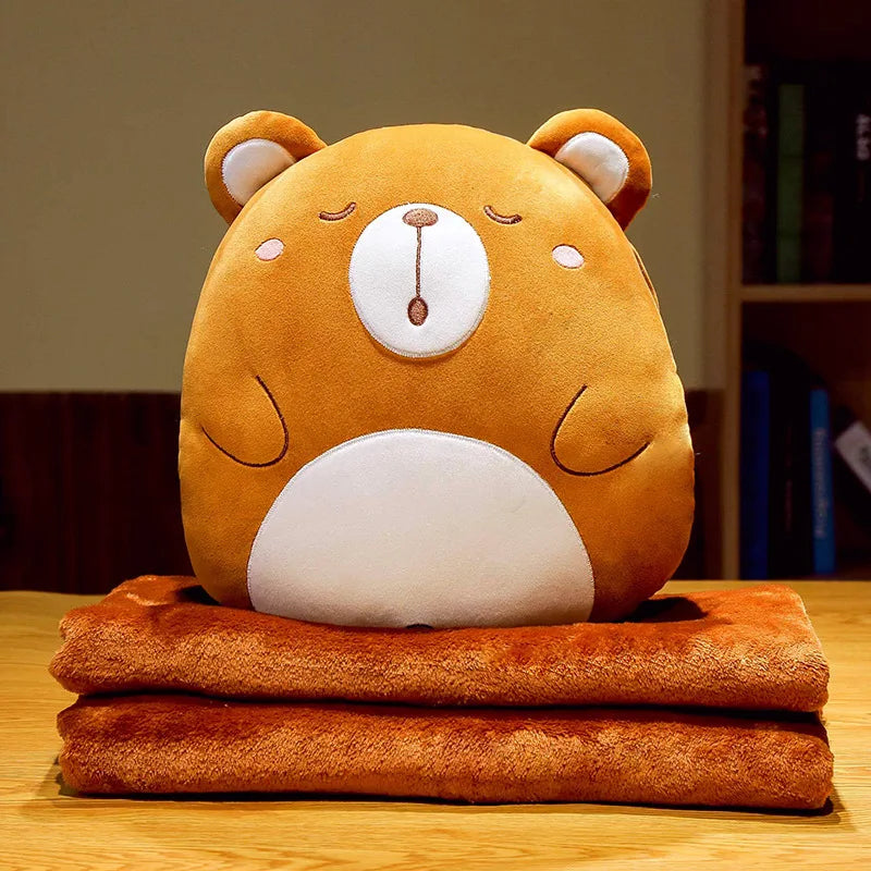 Bear animal cushion blanket with plush orange face on folded orange blanket layers