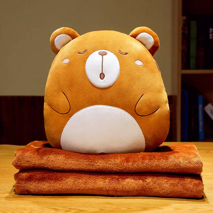 Bear animal cushion blanket with plush orange face on folded orange blanket layers