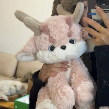 Pink plush dragon with antlers, held up, white muzzle and round black eyes