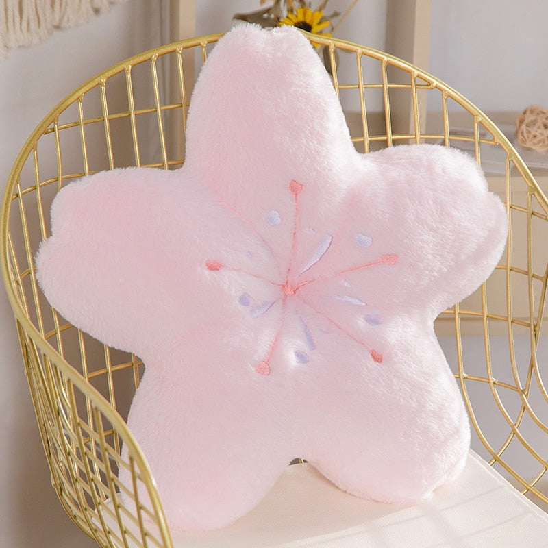 Pink flower-shaped plush pillow with long petal points and embroidered stamen detail
