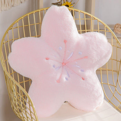 Pink flower-shaped plush pillow with long petal points and embroidered stamen detail