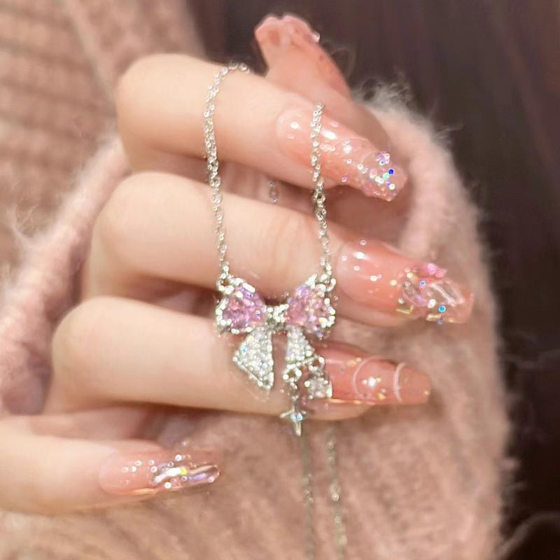 Bow pendant necklace detail: pink crystal bows with silver-toned chain and charms