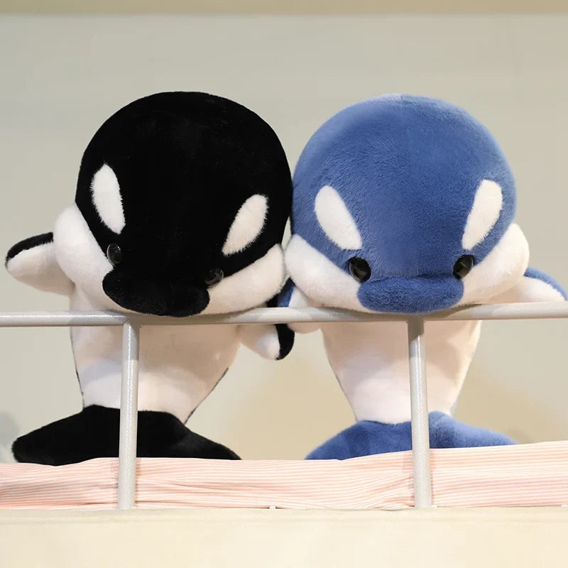 Black and blue dolphin plush pair resting on a ledge, facing forward.