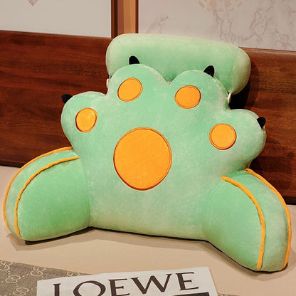 Mint green cat-paw reading pillow with yellow circle face features and curved seams