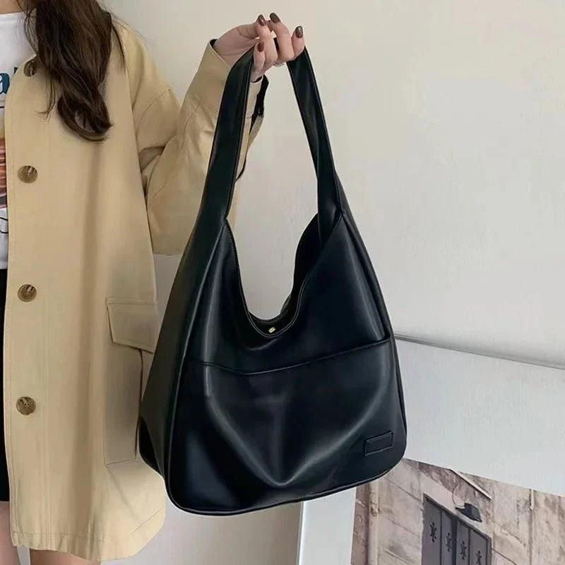 Black leather shoulder tote bag with rounded U-shaped handle opening