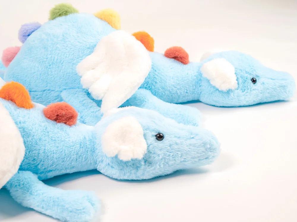 Rainbow dragon plush toy close-up, light blue body with white paws and multicolor orange pom accents
