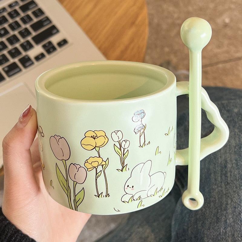 Light green bunny flower mug with illustrated rabbits, flowers, and a spoon-shaped handle