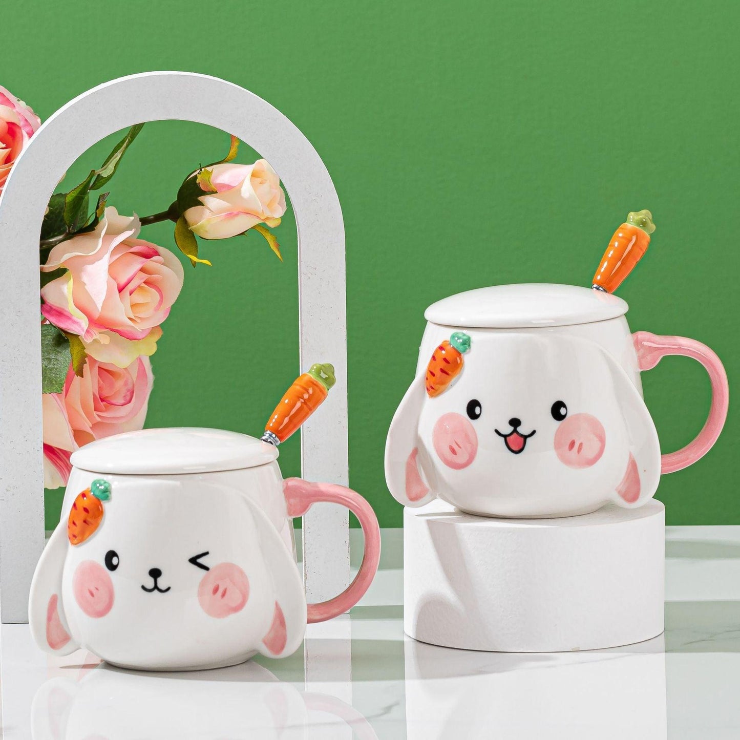 Set of two rabbit ceramic mugs with lids and carrot spoons, pink handles, white bodies.