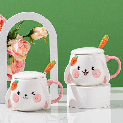 Set of two rabbit ceramic mugs with lids and carrot spoons, pink handles, white bodies.