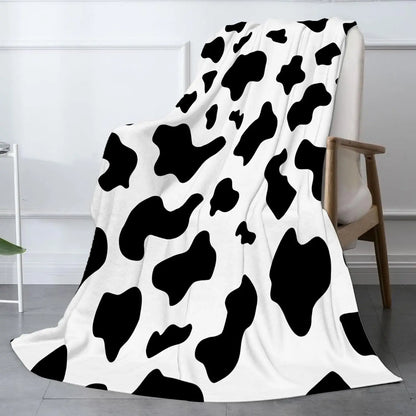 Cow print flannel blanket in black and white, draped over the floor