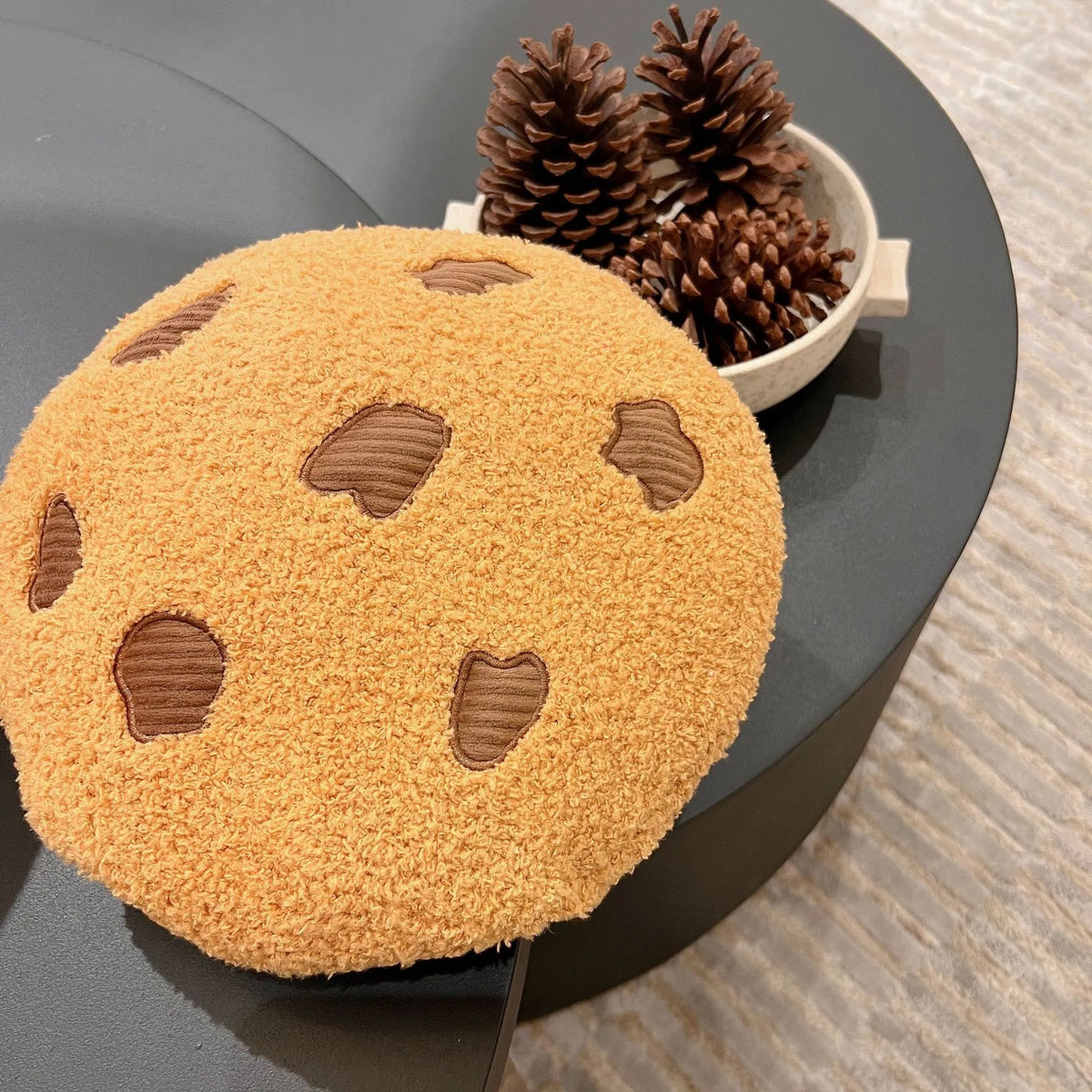 Round tan cookie plush pillow with brown stitched chocolate-chip shapes