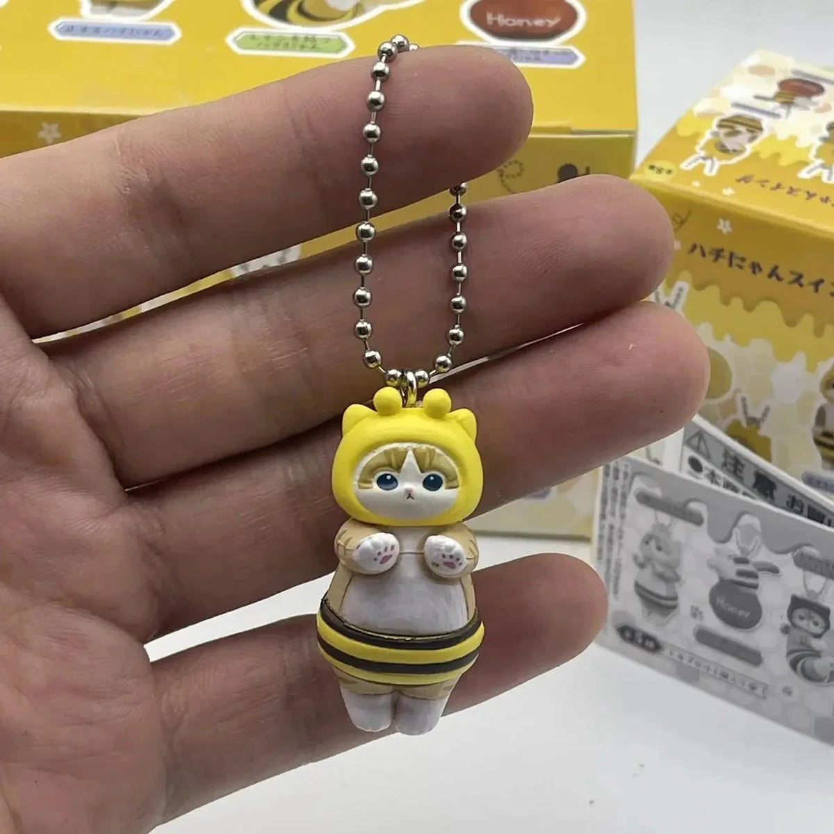 Bee-shaped twisted egg figure keychain on a silver bead chain with dangling face