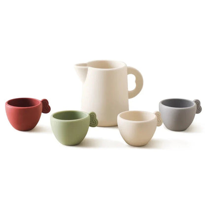 White wooden teapot with handle, and colored cups on wooden saucers