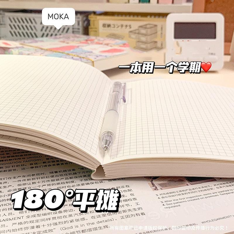 Notebook open showing grid pages and clear spiral binding