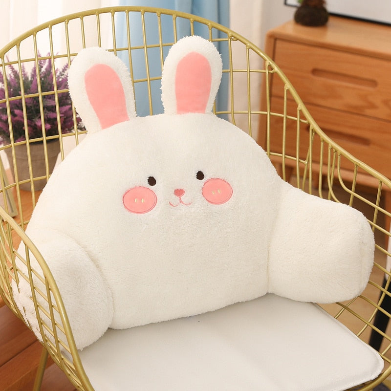 Plush white bunny cushion with pink cheeks and long upright ears in a chair.