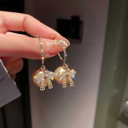 Gold-tone bow drop earrings with glittery ribbon and small dangling charm