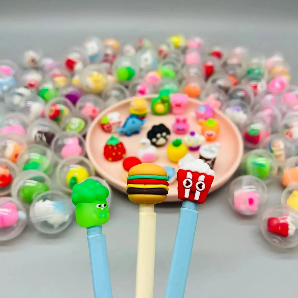 Transparent capsule eggs surrounding a round tray of small toy charms and figures