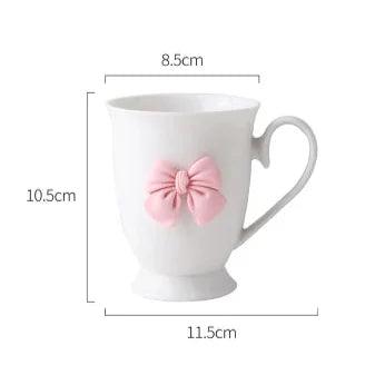 White coffee mug with pink bow on front and curved handle