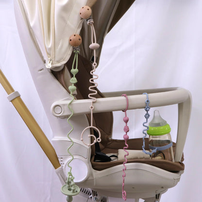 Silicone pacifier chain set hanging from stroller tray rails with teether clips