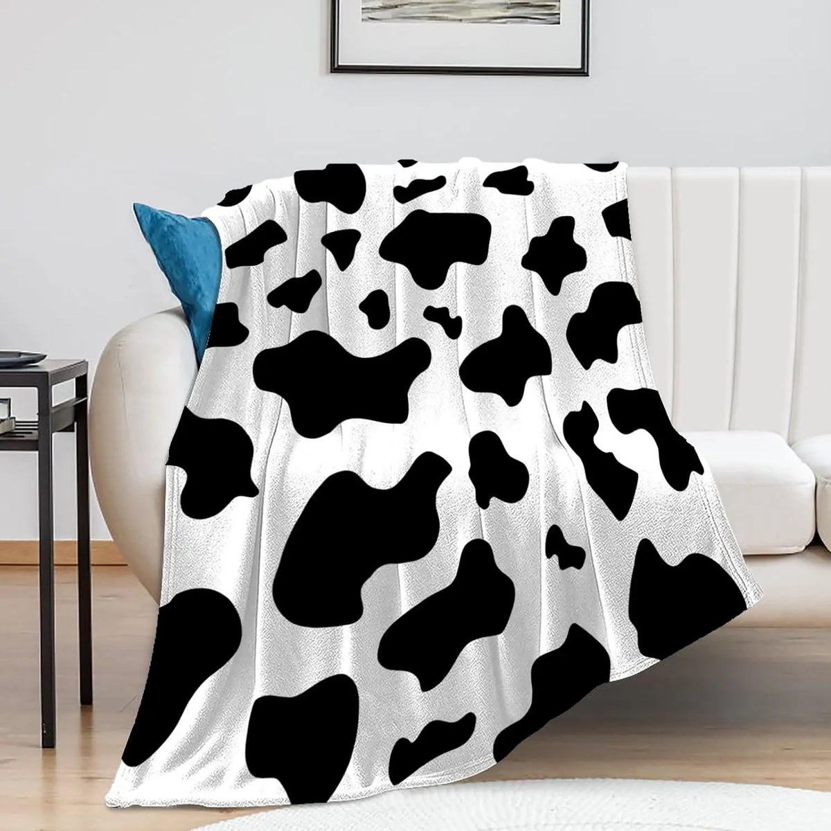 Cow print flannel blanket in black and white, draped over a couch