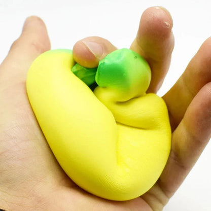 Jumbo squishy banana toy squeezed in a hand, yellow with green end