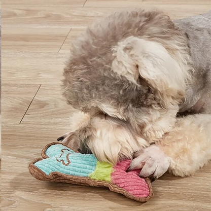 Plush squeaky bone toy on floor, blue and pink with green stripe, brown fabric edges.