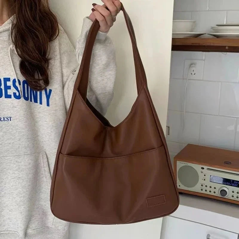 Brown leather slouchy shoulder tote bag with wide straps and front patch
