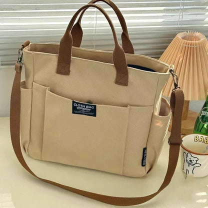 Khaki canvas tote bag with two top handles and wide diagonal shoulder strap
