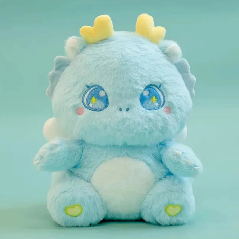 Light blue baby dragon plush close-up with sleepy star eyes and yellow horn tips