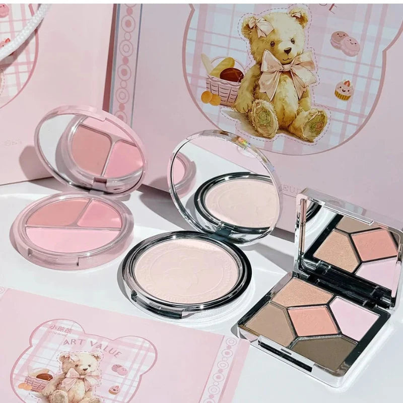 Assorted makeup compacts and eyeshadow palette displayed in a pink gift box set