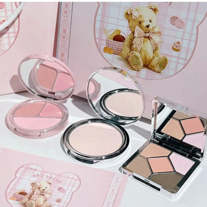 Assorted makeup compacts and eyeshadow palette displayed in a pink gift box set