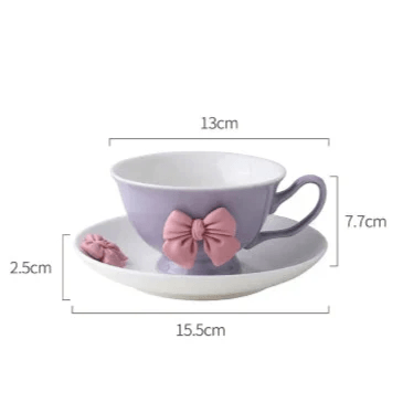 Purple teacup and saucer set with pink bow decoration and right-side handle