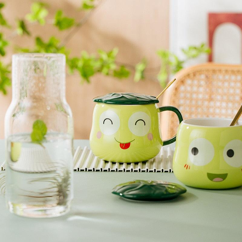 Frog-shaped mug set with lid and spoon, lime green frog mugs on table with frog faces