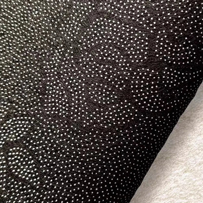 Dark speckled rug backing fabric close-up with dense woven texture.