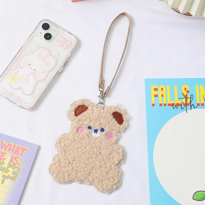 Tan plush animal photo card sleeve with lanyard strap next to smartphone