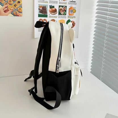 White cute bear backpack shown from the side with a top zipper and black shoulder straps