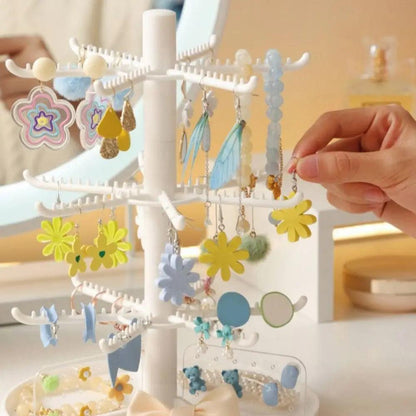 White tiered earring display stand with multiple hook rows and dangling earrings