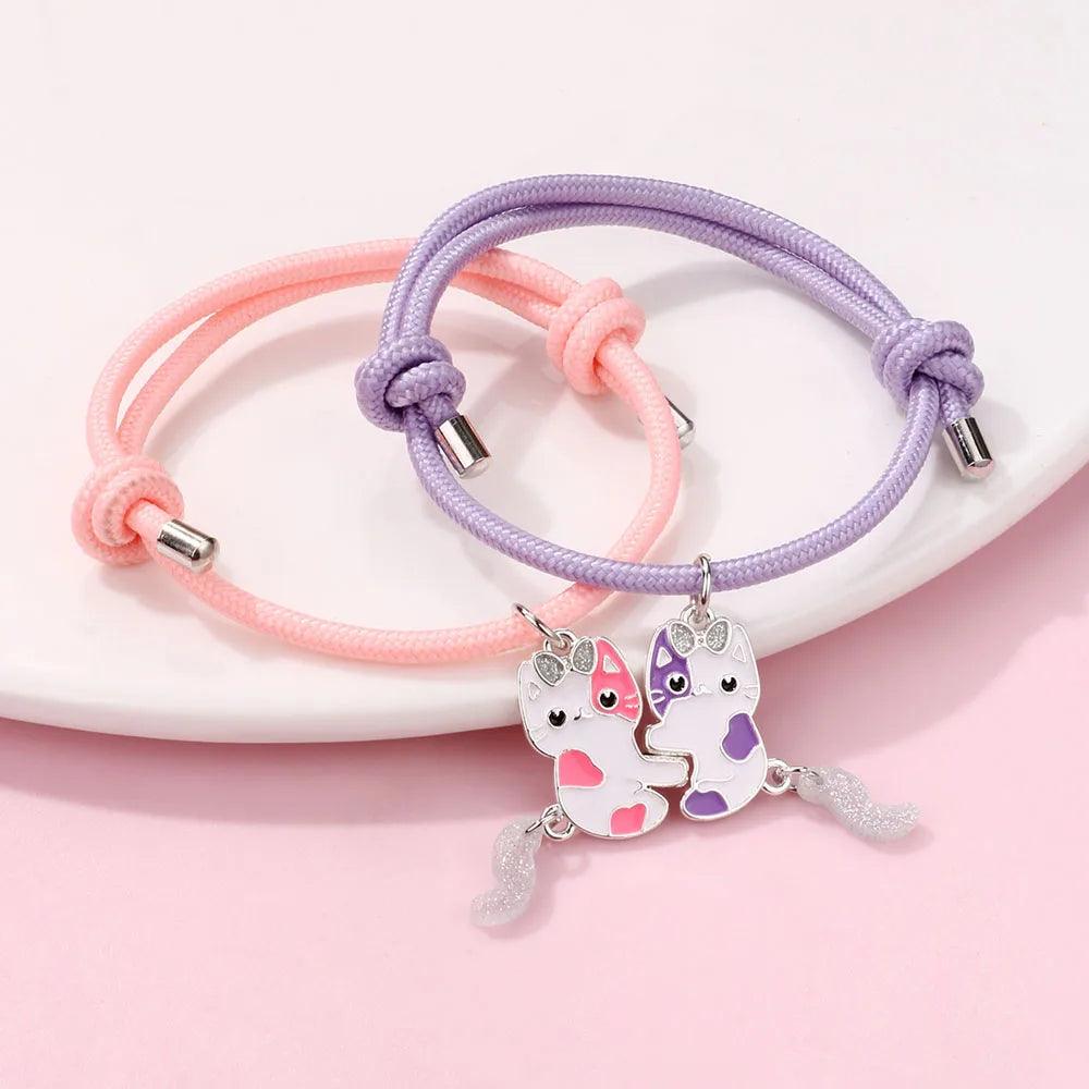 Top view friendship bracelets with pink and lavender braided bands, cat charms, silver spacers