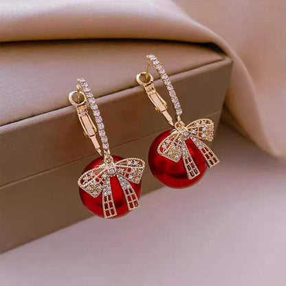 Gold-tone ornament hoop earrings with red bauble and rhinestone bow charm
