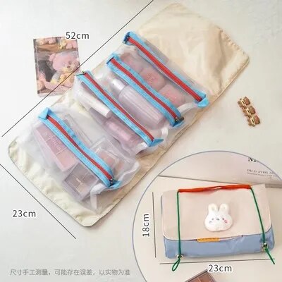 Roll-up travel makeup bag with four clear zip pouches and small bunny patch, cream fabric
