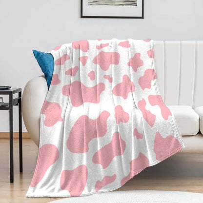 Cow print flannel blanket in pink and white, draped over a couch