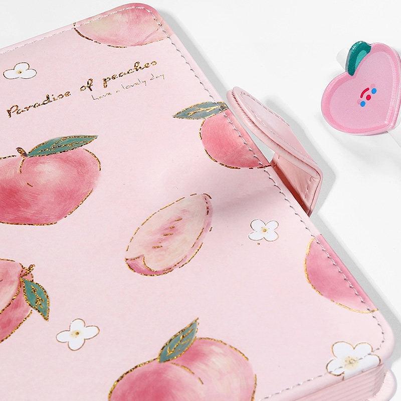 Pink notebook cover with peach illustrations, stitched edges, and decorative flap detail