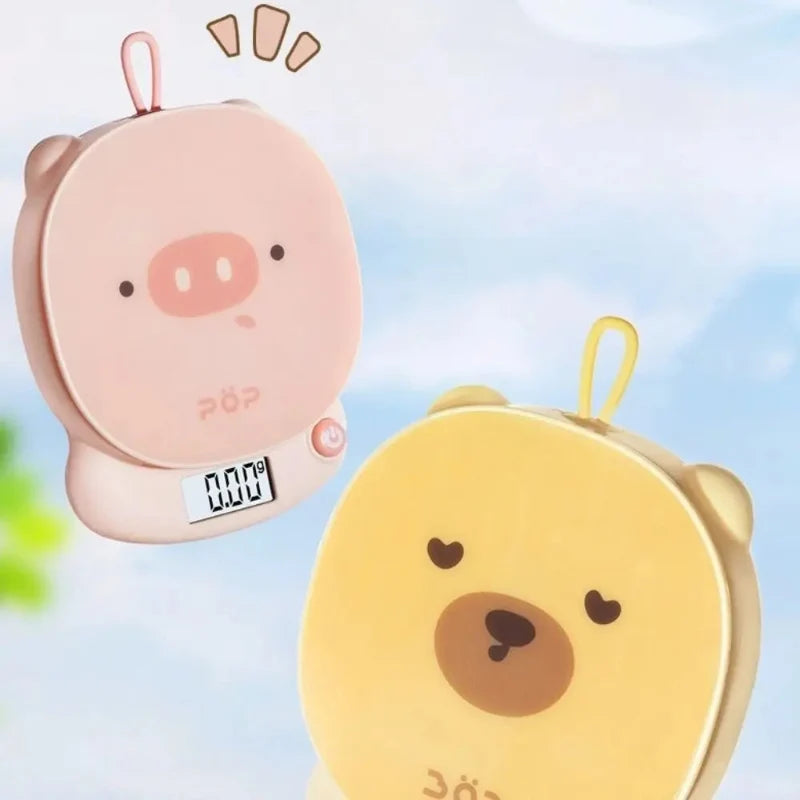 Pink pig-face and yellow bear-face digital kitchen scales side by side