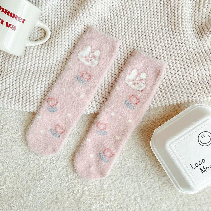 Bunny socks in pastel pink and white with paw prints and small multicolor heart accents.