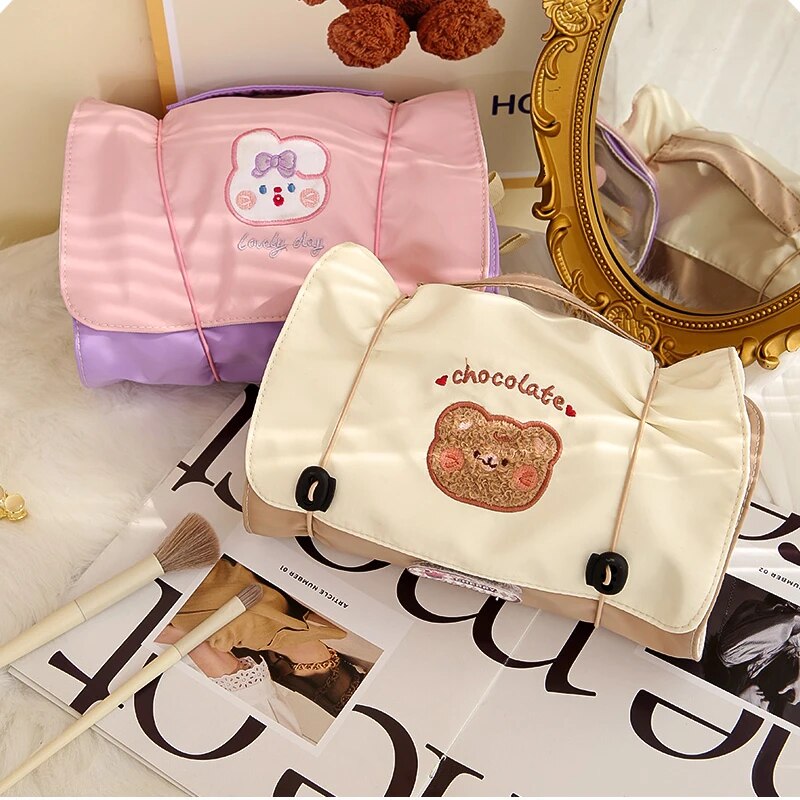 Pink and cream roll-up makeup bags with cartoon bear patches and snap-corner straps