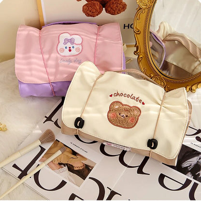 Pink and cream roll-up makeup bags with cartoon bear patches and snap-corner straps