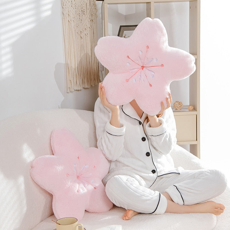 Pink cherry blossom plush pillows on couch, person holding one embroidered flower cushion