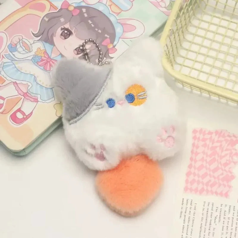 Gray cat plush keychain with blue-and-yellow face and orange paws, metal chain