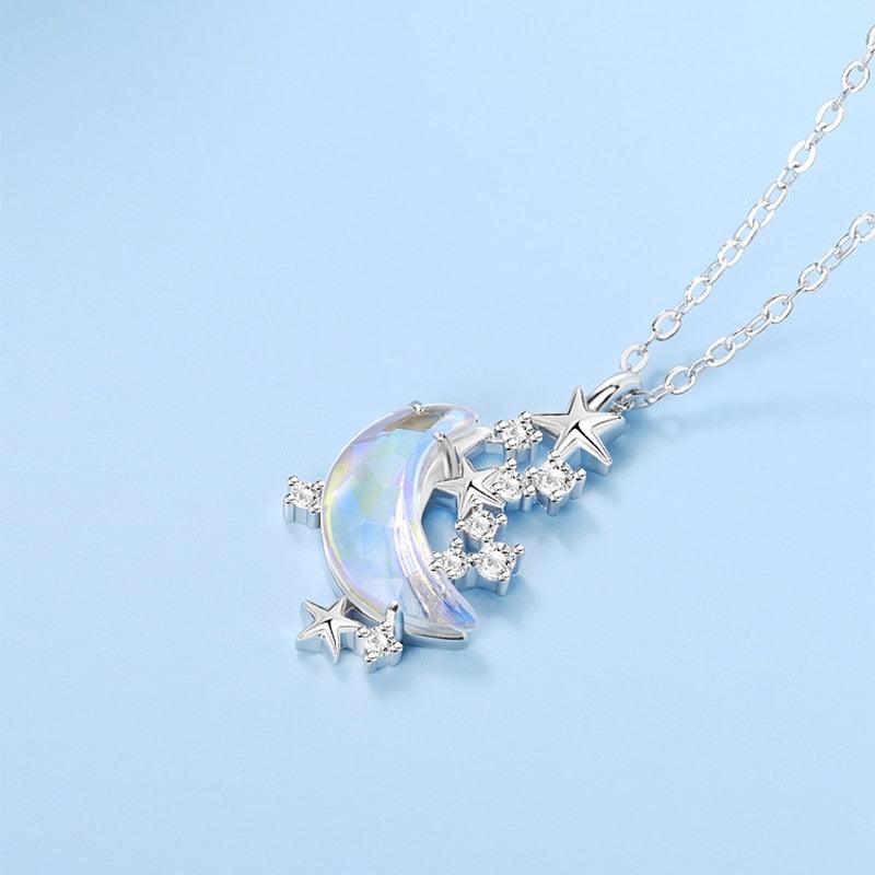 Glazed crescent moon pendant necklace with blue iridescent stone, star charms, and crystal details